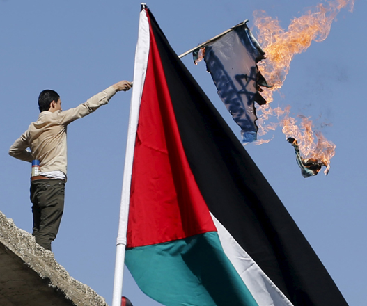 A protester burns an Israeli flag during a march to express solidarity with Palestinians and against the escalation of Israeli aggression after noon prayer in downtown Amman on Friday (Reuters photo by Majed Jaber)